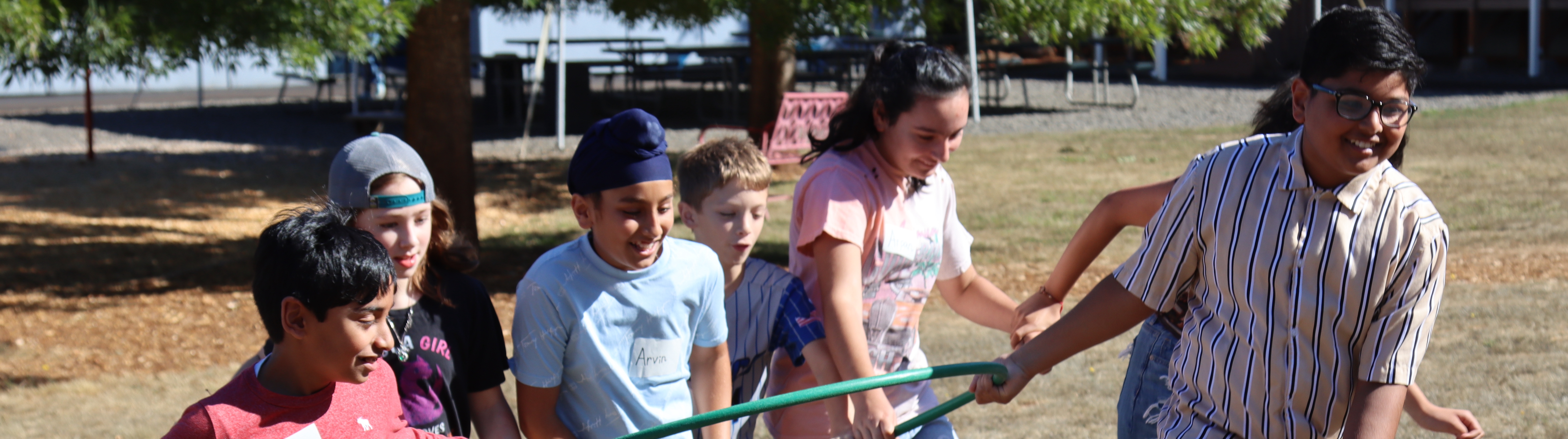students outside pulling on a hose