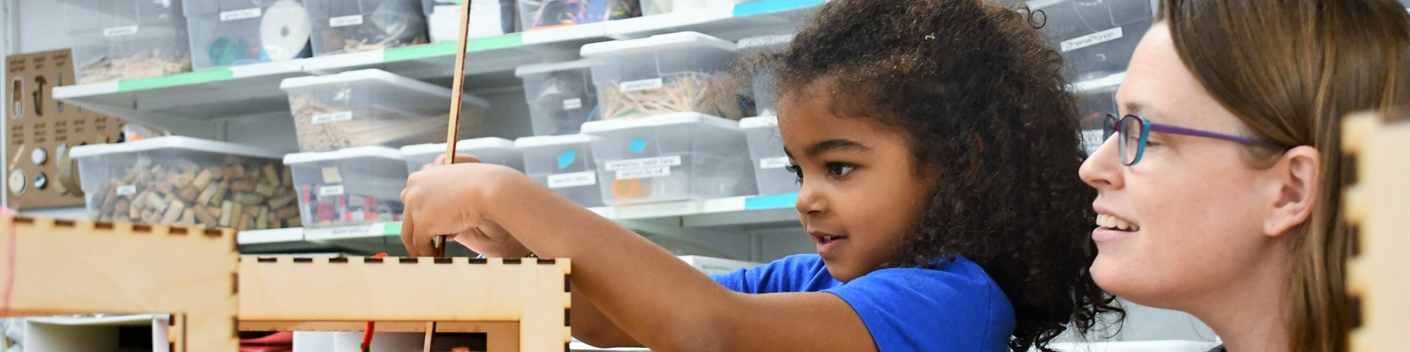 young girl and teacher building a small wooden structure