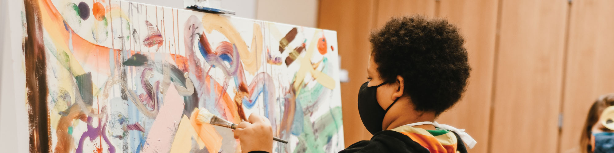 child painting with a black mask on