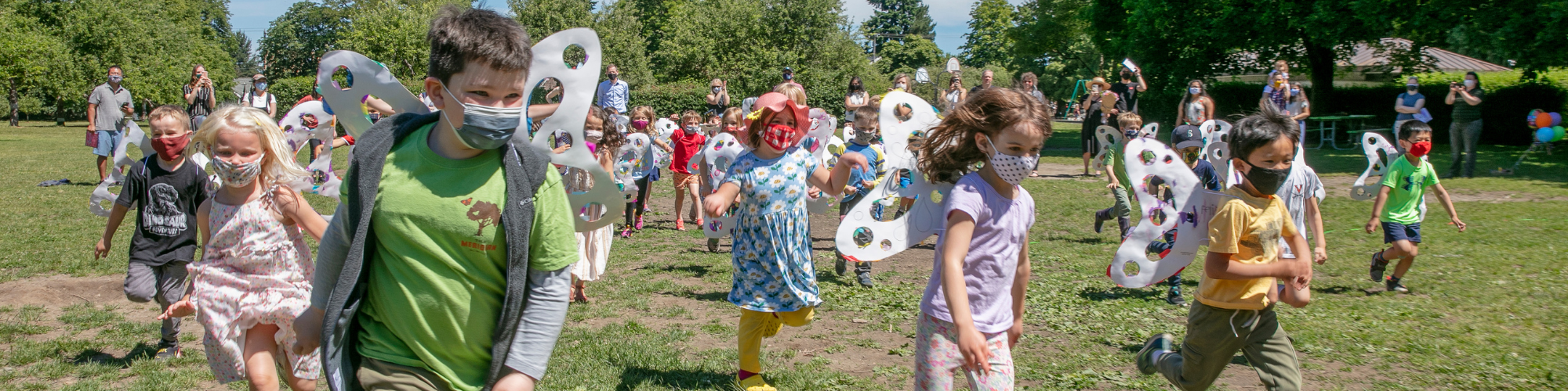 children running outside with attached butterfly shaped wings