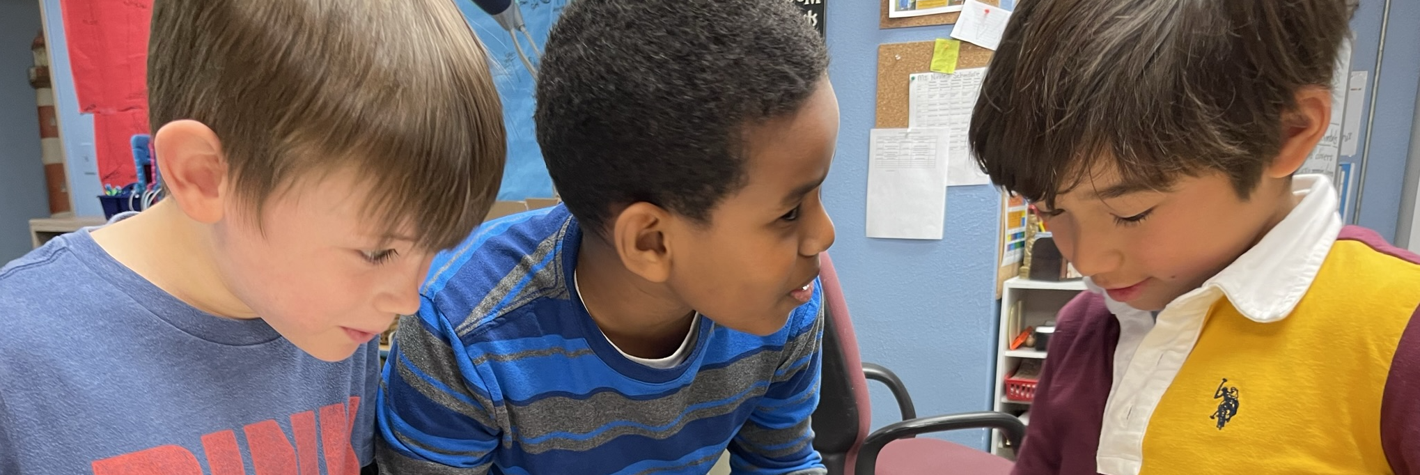 3 young boys chatting in a classroom