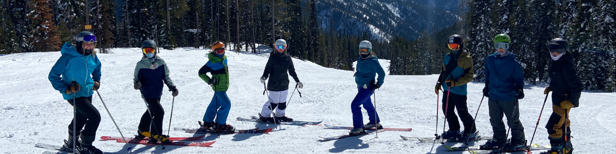 students in ski attire and equipment standing in a row on the snow
