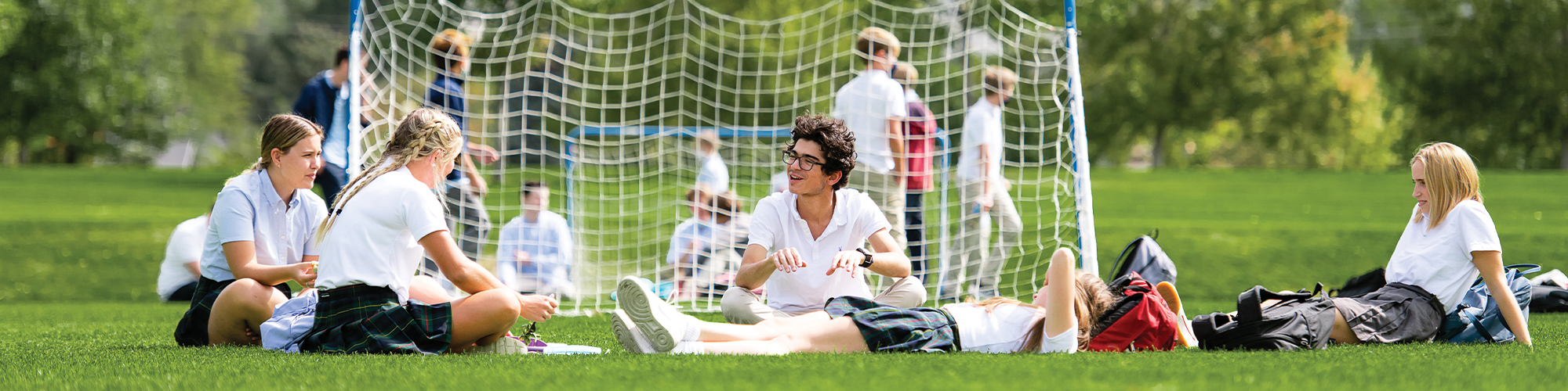 teen students sitting and chatting behind a soccer goal