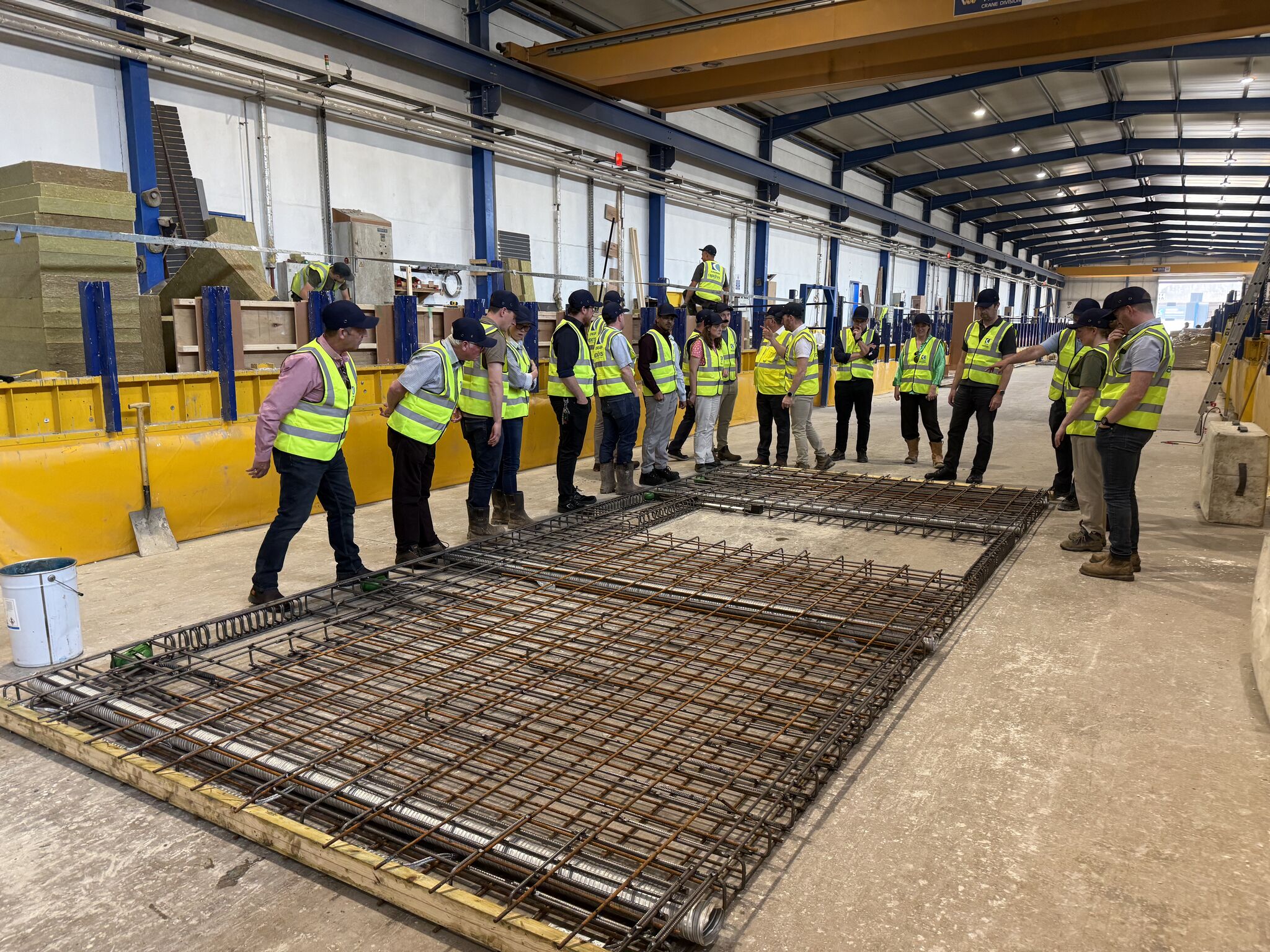 people in high vis vests standing around a metal grid on the floor