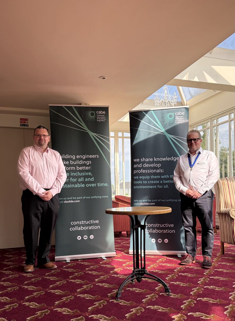 Two men standing in front of CABe roller banners