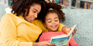 Photo of black woman reading book to a child
