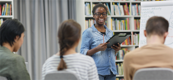 A smiling woman holding a clipboard in an academic library setting