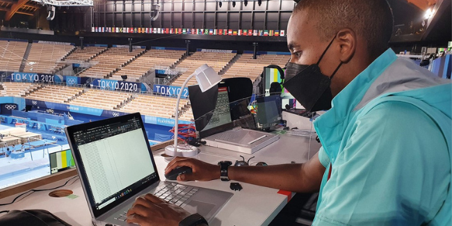 Photo of Nzumbe Nyanduga, Games Analytics Manager, checking the output from data capture sensors at the Gymnastics venue during a training event.