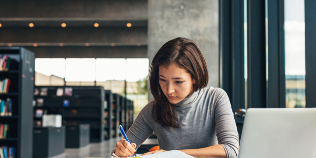 Woman writing at her desk in a library