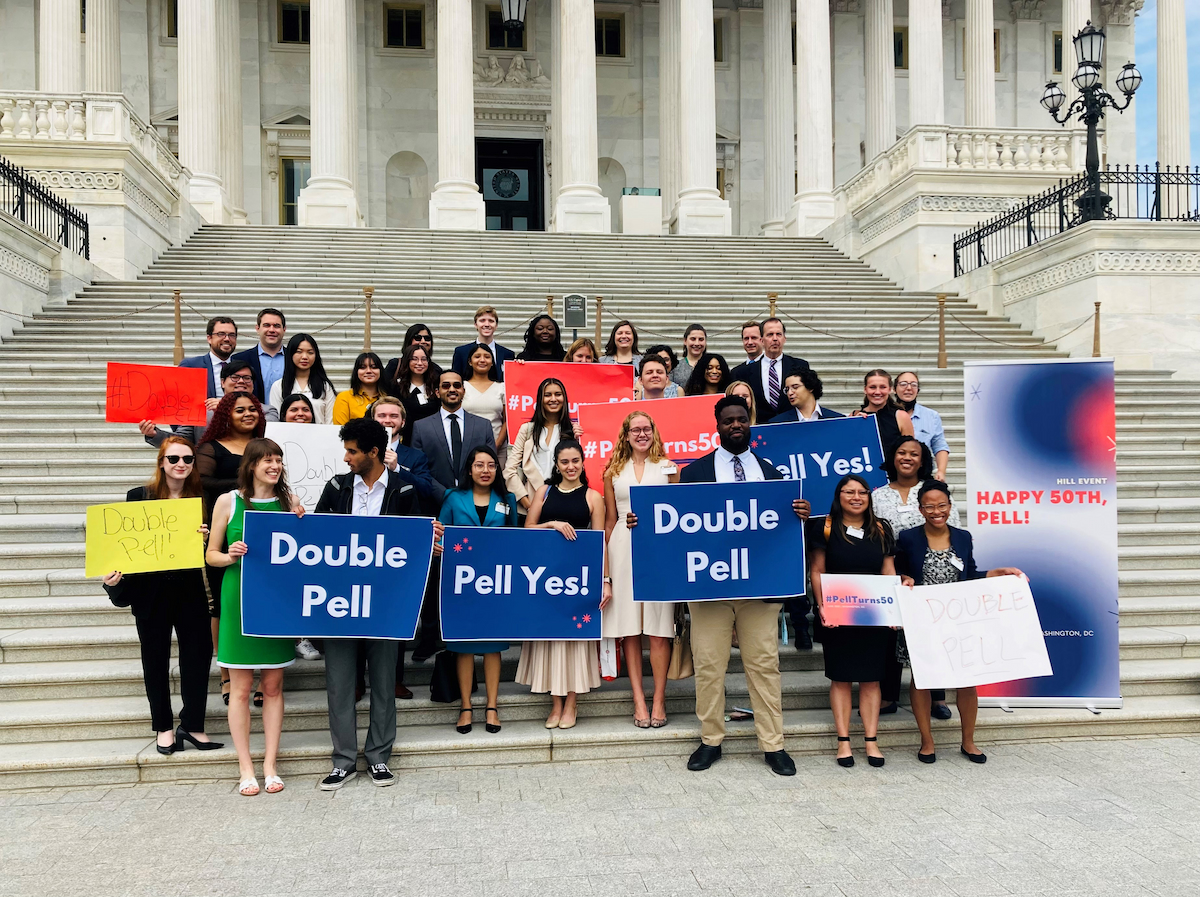 Large group of students and higher education advocates standing on the steps of the United States Capitol Building, carrying signs that say “Happy 50th, Pell!” “Double Pell,” “#PellTurns50,” and “Pell Yes!”