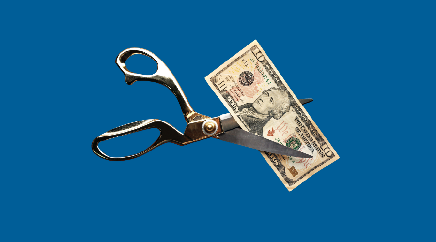 Scissors cutting money on a blue background