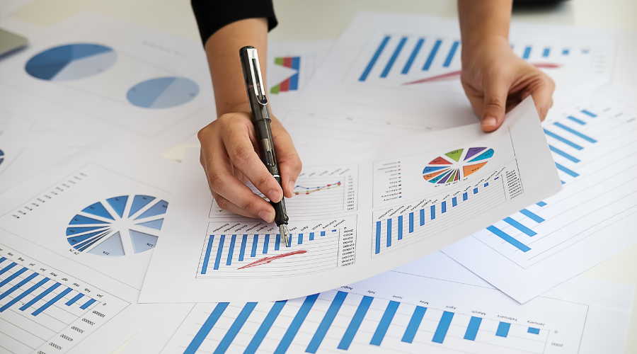Person writing with a pen on printed graphs