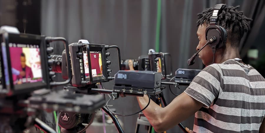 A young Black student, checking his cameras while filming.