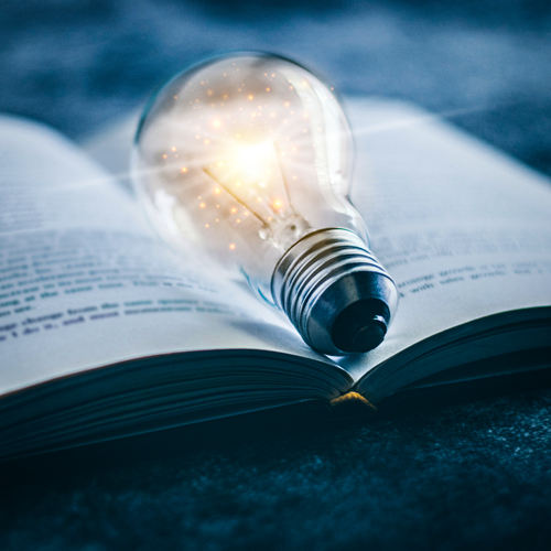 Open book with a glowing light-bulb resting over the center fold