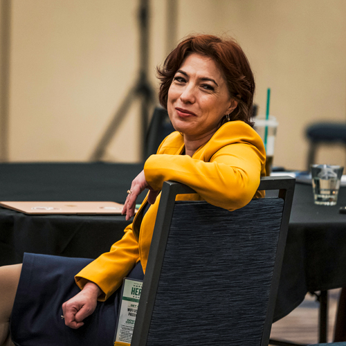 Latinx/Hispanic woman in a yellow blazer smiling at the camera.