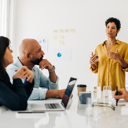 Mixed group of professionals discussing a project with a whiteboard in the background.