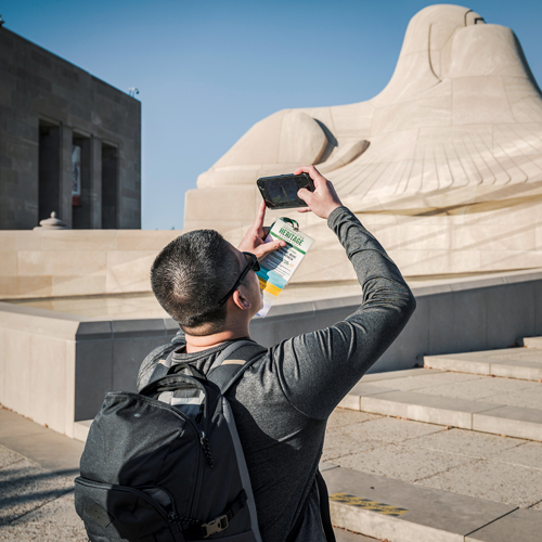 A young male student photographing architecture at a Kansas City park.