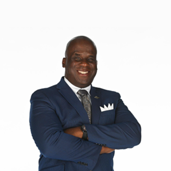 Professional Black man in a blue suit with arms crossed, smiling confidently.