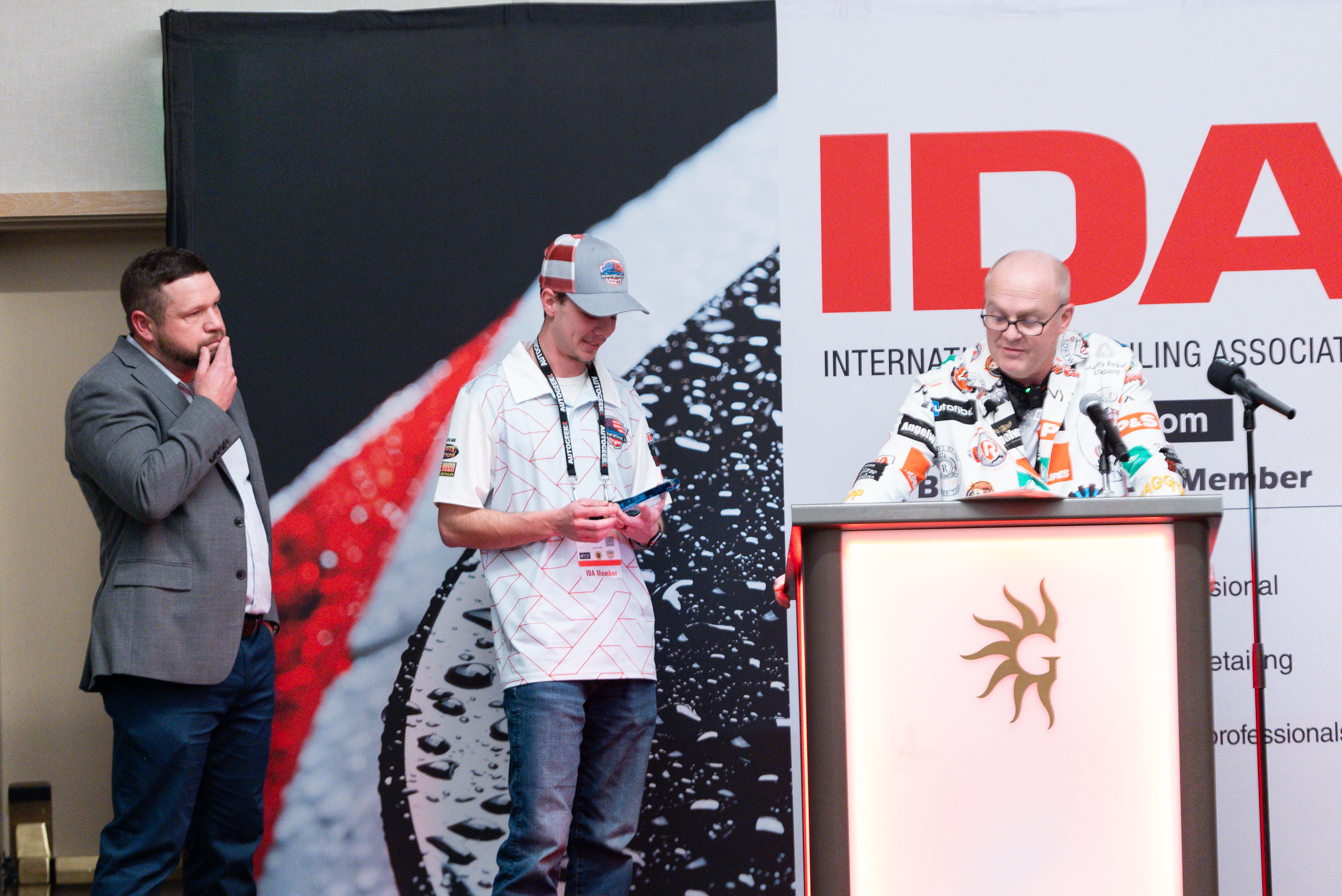 Cody standing on stage, holding and staring at his award in awe, as he waits to take the podium from Rod to speak