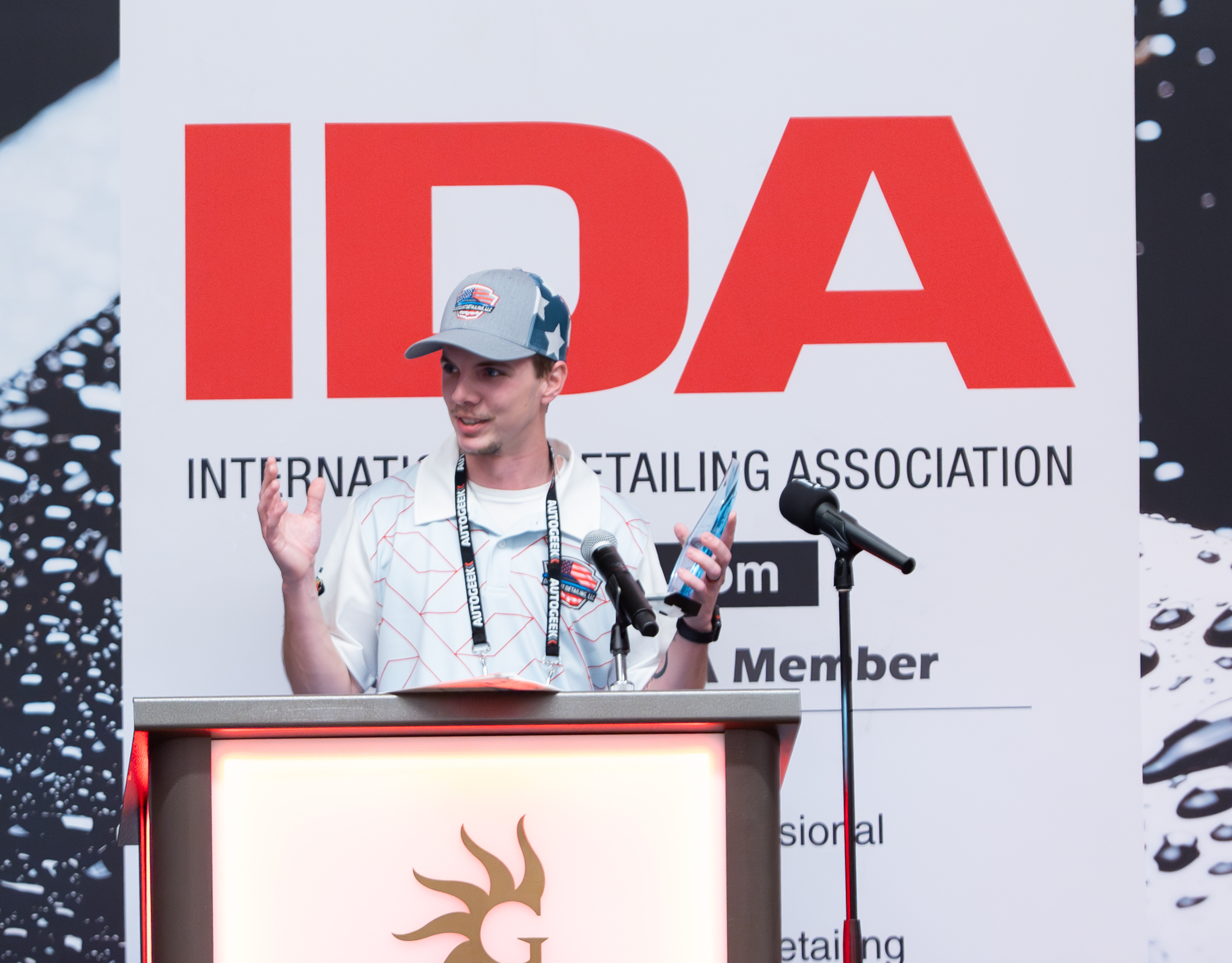 Close up photo of Cody standing at the IDA podium on stage, giving an acceptance speech as he holds his award