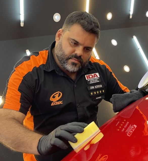 Photo of John Herrison, wearing gloves and detailing a car in his studio