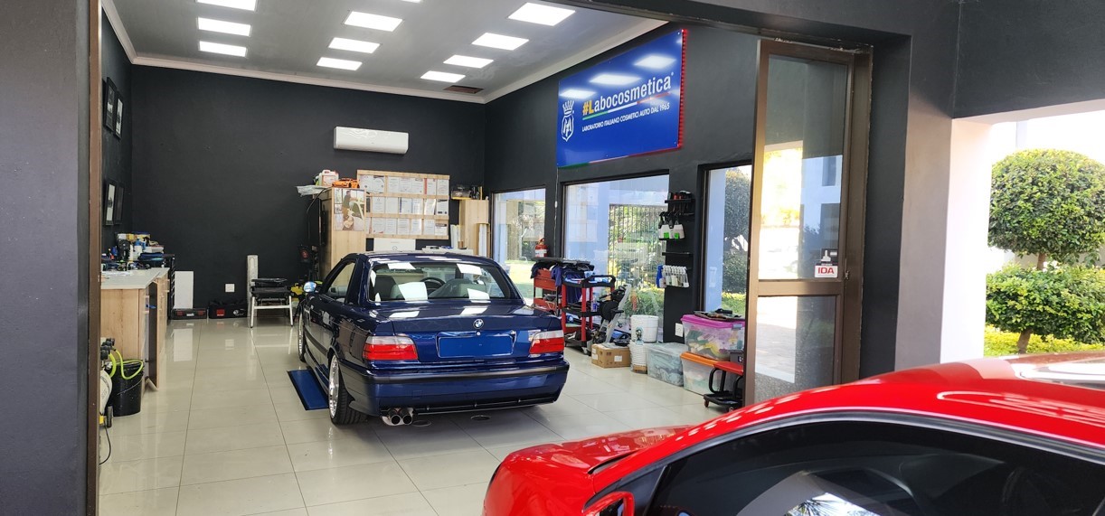 Photo of Hybrid Detailing shop, with two walls open outside and two cars sitting inside.