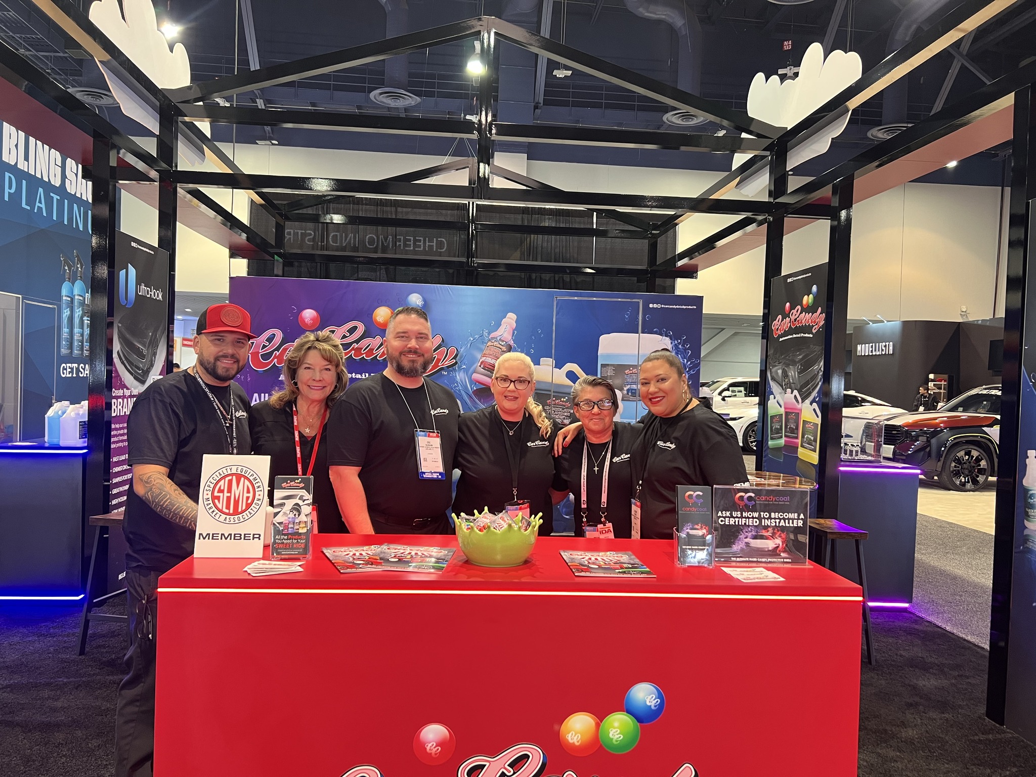 Photo of Car Candy team standing at their red car candy booth at a tradeshow