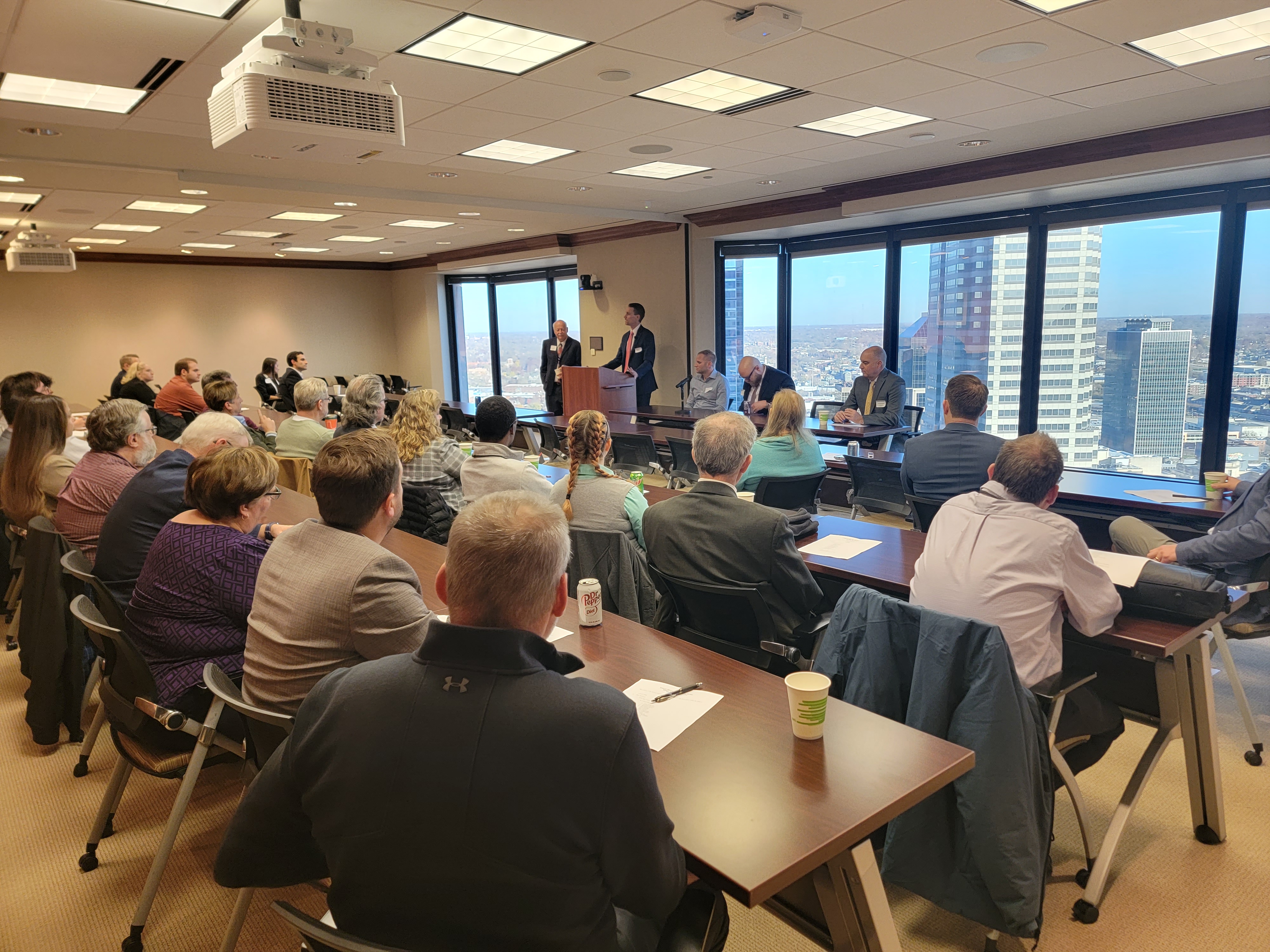 A large group watching a panel of speakers